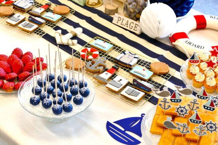 Goûter thème marine pour Axa XL réalisé par studio candy avec une décoration sur mesure, des pâtisseries personnalisées comme des cakepops bleu marine, des sablés ancre, bouée, bateau, coquillage, et une décoration en bleu, blanc et rouge