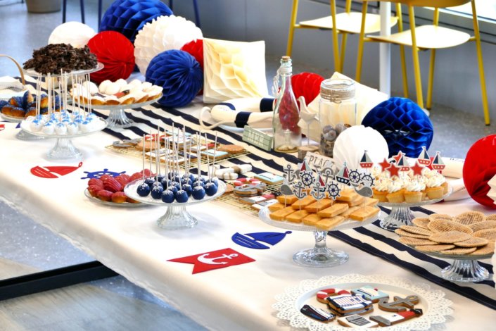 Goûter thème marine pour Axa XL réalisé par studio candy avec une décoration sur mesure, des pâtisseries personnalisées comme des cakepops bleu marine, des sablés ancre, bouée, bateau, coquillage, et une décoration en bleu, blanc et rouge
