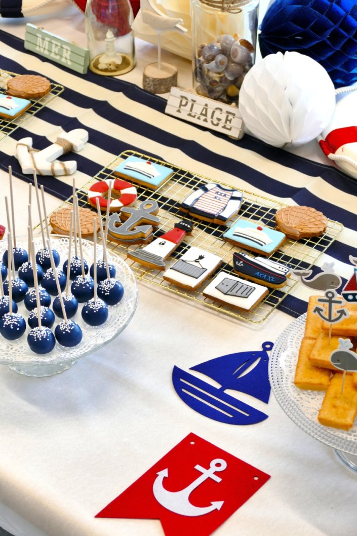 Goûter thème marine pour Axa XL réalisé par studio candy avec une décoration sur mesure, des pâtisseries personnalisées comme des cakepops bleu marine, des sablés ancre, bouée, bateau, coquillage, et une décoration en bleu, blanc et rouge